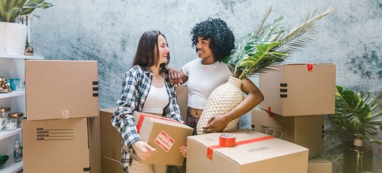 Two women moving boxes to storage