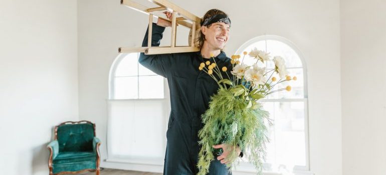 a man holding a chair and a plant