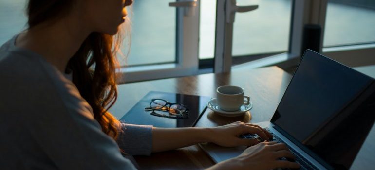 a woman typing on laptop trying to organize a successful relocation to Miami