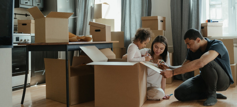 parents playing with their daughter by drawing on a cardboard box