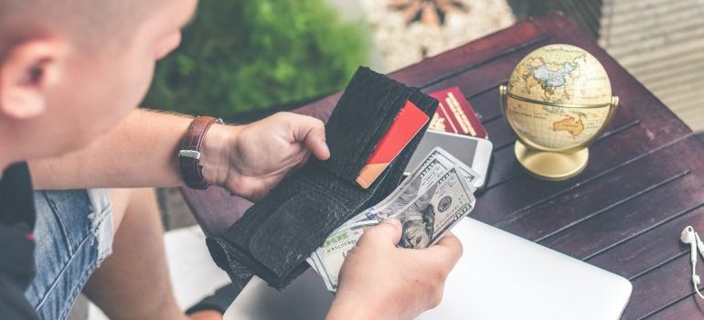 A person holding a wallet and dollar bills. 