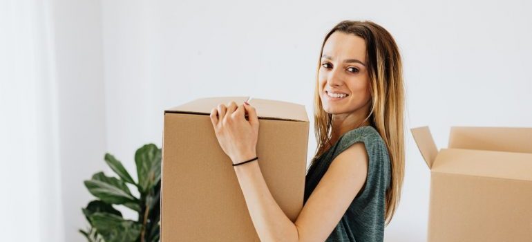 A happy woman holding a moving box