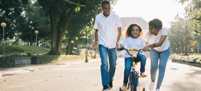 Mother and father teaching their daughter how to ride a bike