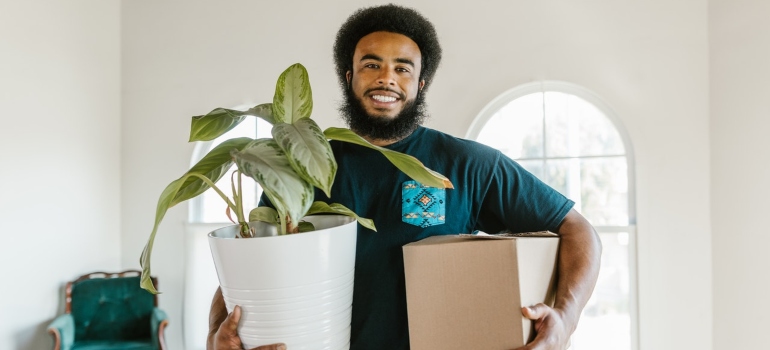 A mover carrying a house plan and a moving box