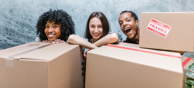 three happy people behind cardboard boxes