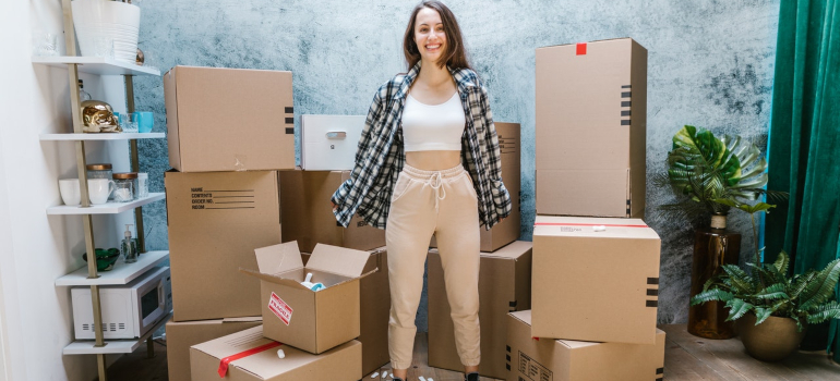 a woman standing happilly between cardboard boxes