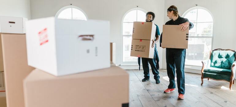 A couple of movers holding moving boxes