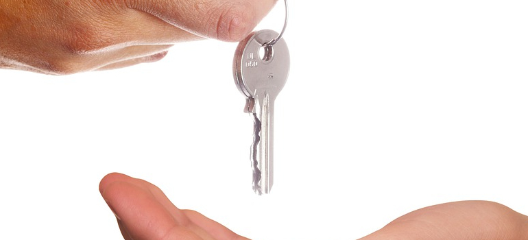 two hands and a key, symbolizing dilemma of whether to buy or rent office space for your Miami-based business