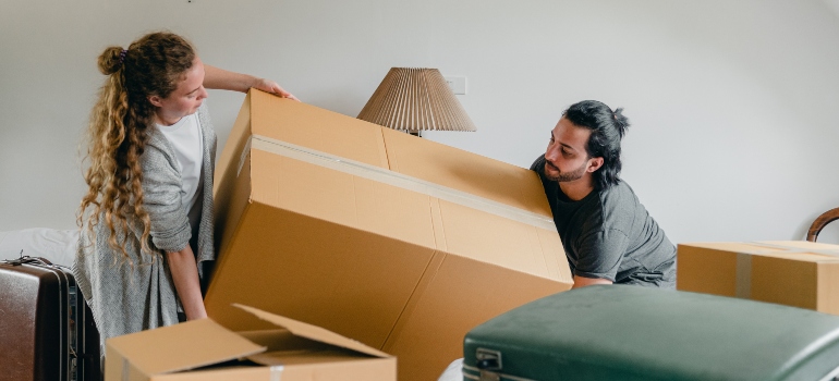 A man and a woman are carrying a box