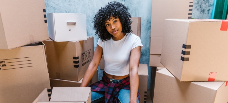 A woman sitting on a chair surrounded by cardboard boxes