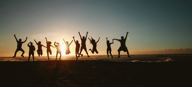 people jumping on the beach during sunset