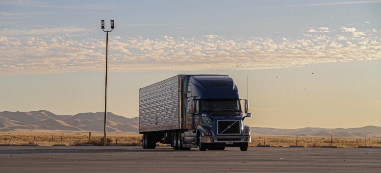 Moving truck at the parking, with hills and sky at the back.