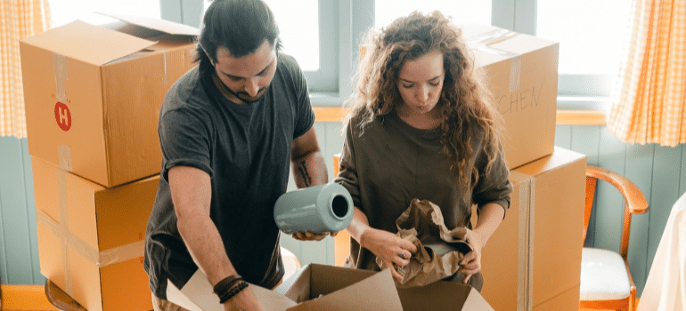 a man and a woman trying to pack items for moving