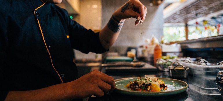 a chef sprinkling sesame seeds on the food