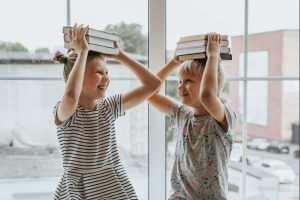 Two kids with books on the heads - education is important when moving to Miami