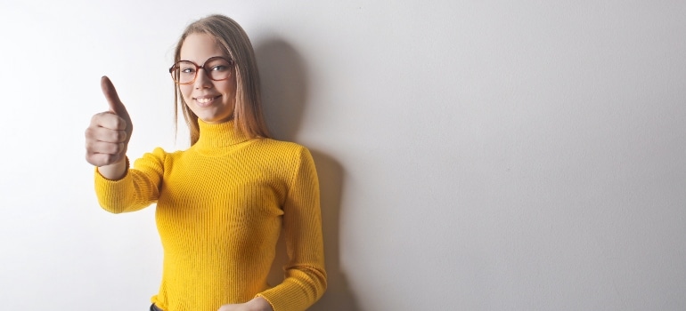 smiling blonde woman in turtleneck showing thumbs up