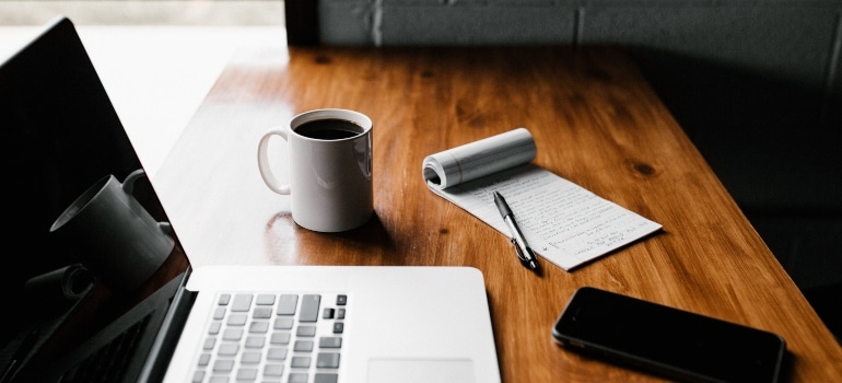 laptop, mug, smartphone, and notepad on the table