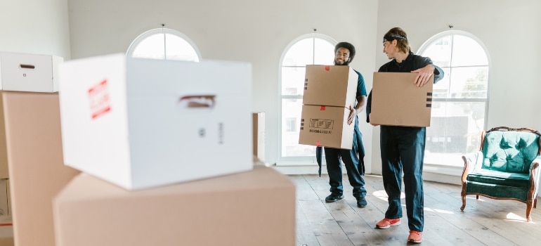 two guys in blue carrying boxes