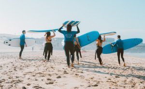 people on the beach holding surfing boards