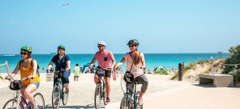 people riding their bikes by the beach