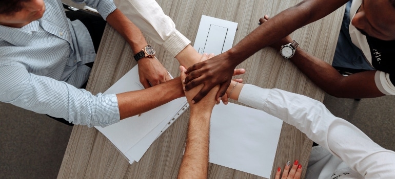 multiple people putting their hands together