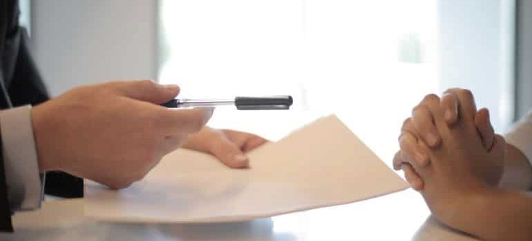 a man offering a pen to a woman in order to sign a contract