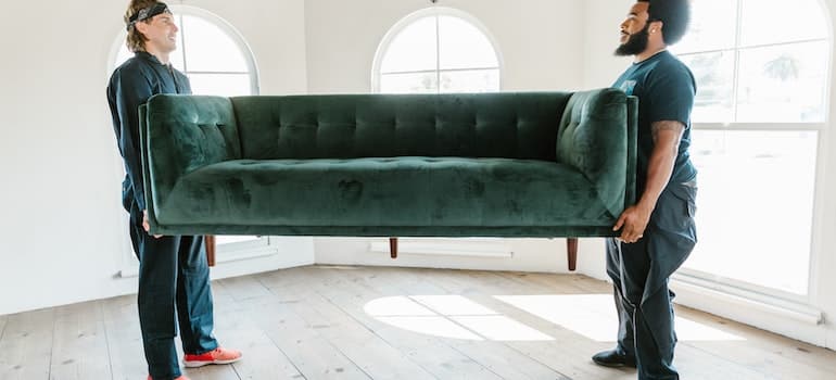 Two men carrying a green couch