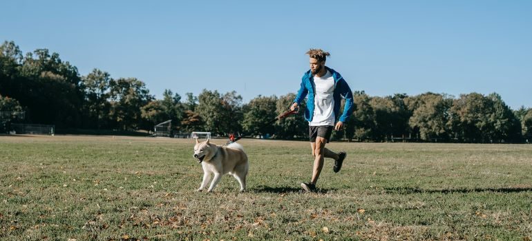 a amn running with his dog in the park