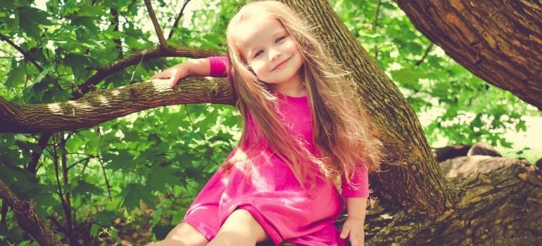 a girl playing on a tree in a park