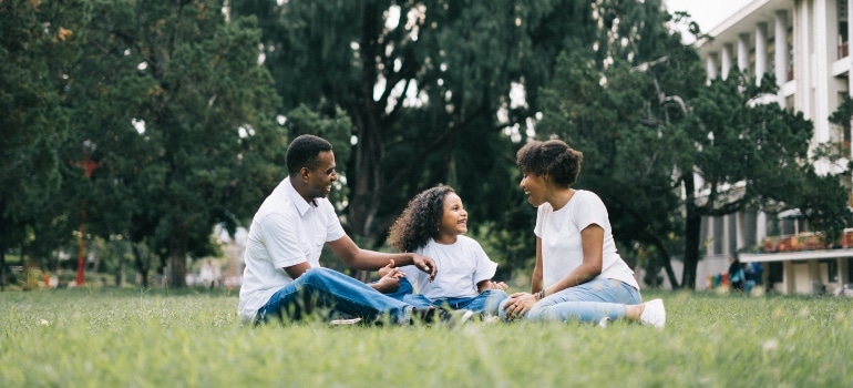 parents sitting in the park with their kid in one of the best places to live in Palm Beach County