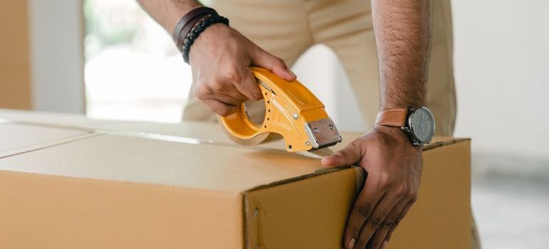 a man sealing the box with a tape