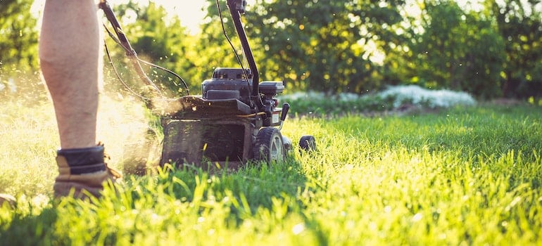 man mowing the lawn as part of the process to clean your old home after moving