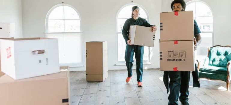 Two movers carrying boxes inside the house