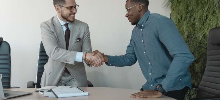 two people shaking hands before they deal with clutter when moving office