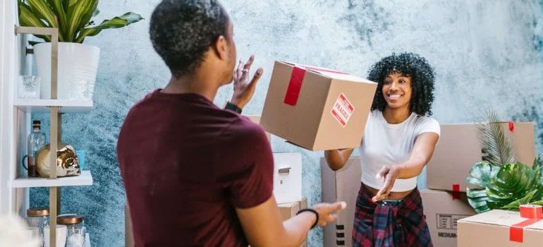 Two movers throwing a moving box to each other