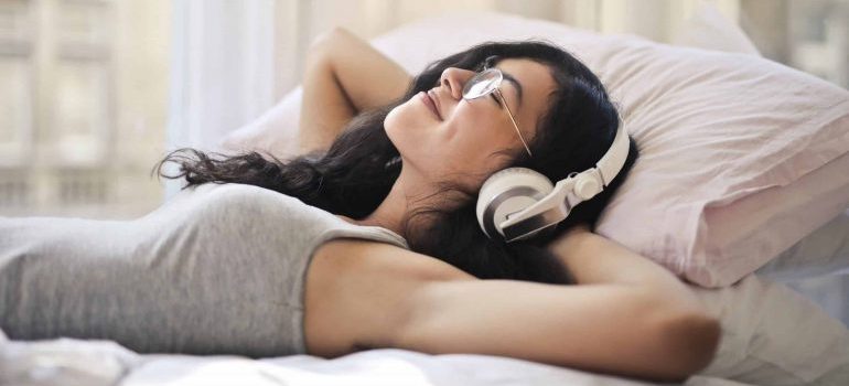 A young woman listening to music and relaxing to deal with stress when moving to Fort Lauderdale.