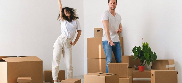 A happy couple dancing in the room with moving boxes.