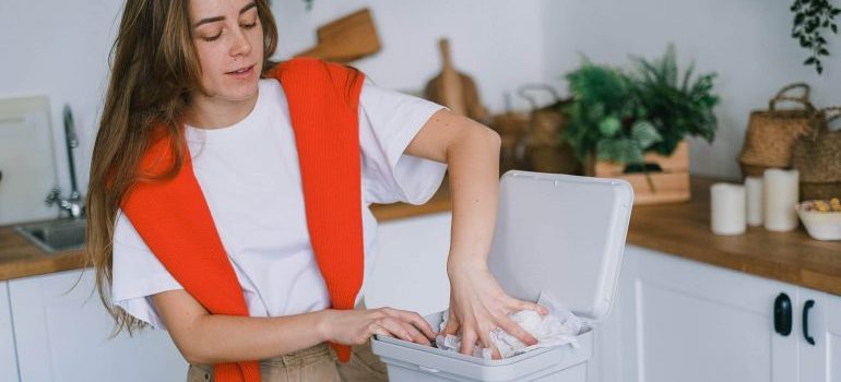 A woman putting some papers in the bin and thinking about tips and trick for a green storage in Miami