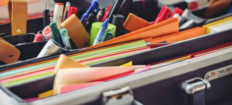 A suitcase with a lot of pens and papers