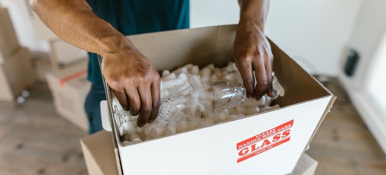 A person packing items in a box in order to relocate from Hallandale Beach to Miami.