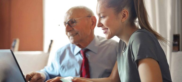 A young woman and an elderly man looking at the laptop.