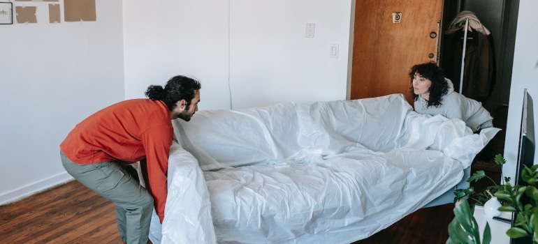 A couple moving heavy furniture.