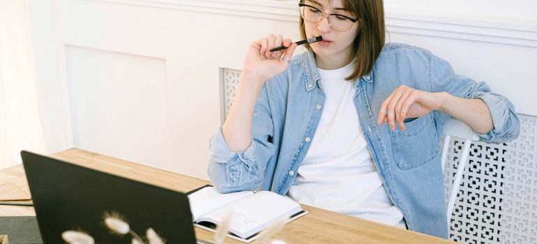 A young woman looking at her laptop and thinking how to make moving to Boca Raton easier.