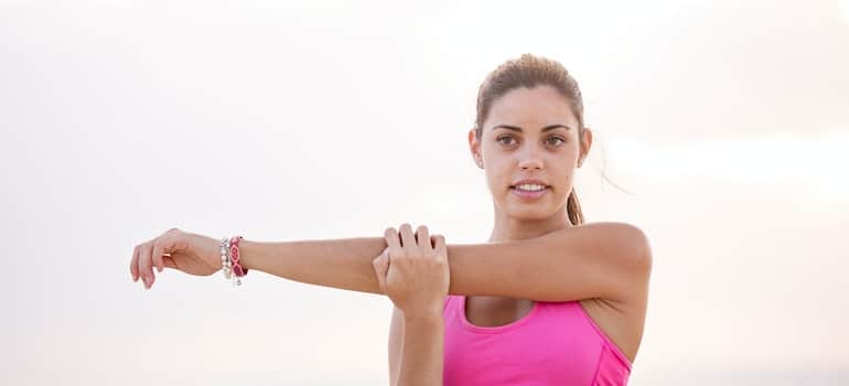 A girl stretching outside after joining local yoga club as a way to make friends after moving to Miami.