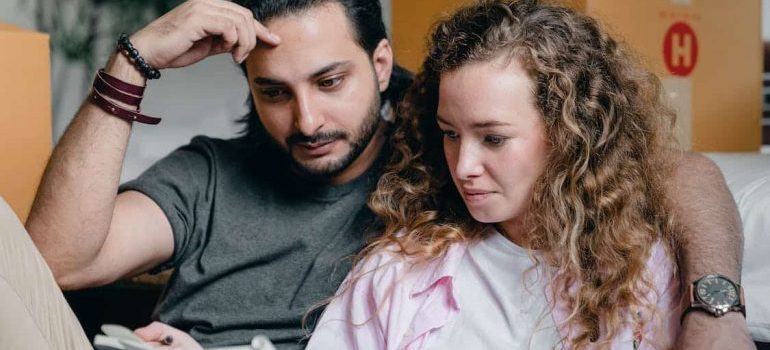 A couple looking at the computer and thinking how much money do you need for a long distance move.