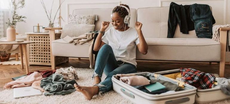 A young woman packing while listening to music.