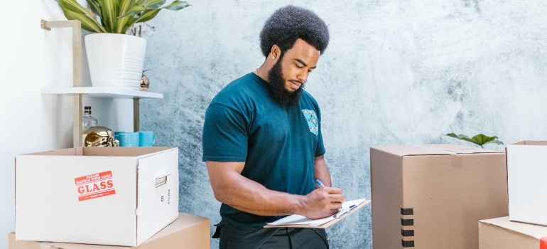 A professional mover writing on a clipboard.