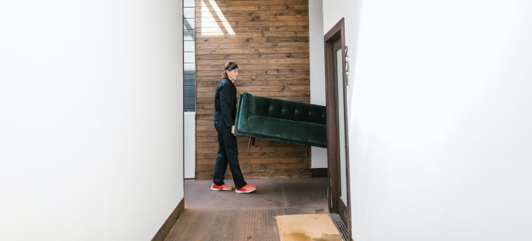 Professional movers carrying a sofa through a hallway.