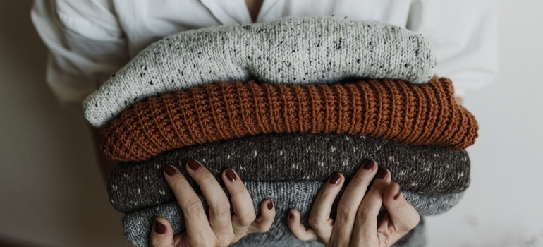A person holding sweaters.