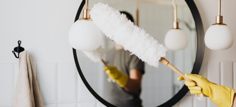 A person dusting a light fixture.